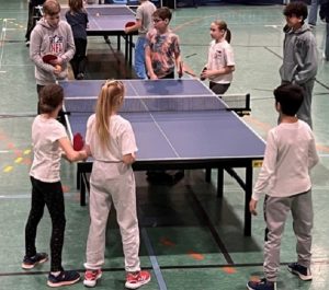 Kinder spielen Tischtennis in der Sporthalle.