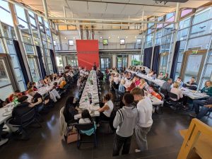 Große Mensa mit vielen Menschen an langen Tischen